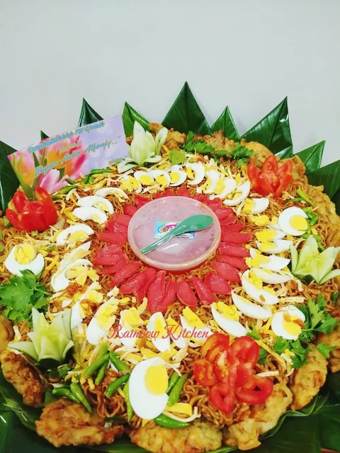 Mi goreng nampan berhias telur rebus, irisan sosis merah, tomat dan cabai hijau dengan kartu ucapan