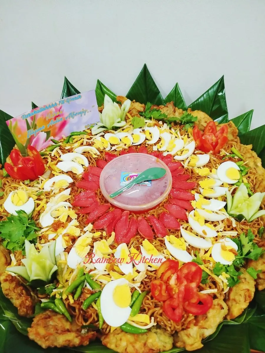 Mi goreng nampan berhias telur rebus, irisan sosis merah, tomat dan cabai hijau dengan kartu ucapan