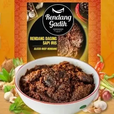 Semangkuk rendang daging sapi iris di depan kemasan hitam Rendang Gadih, dikelilingi cabai, bawang, dan rempah
