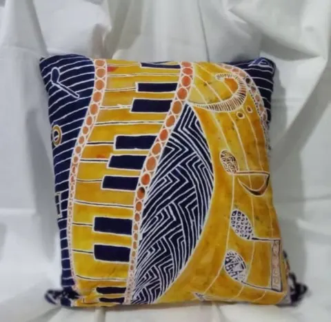 Sarung bantal batik bermotif kuning, oranye dan biru tua di atas kain putih
