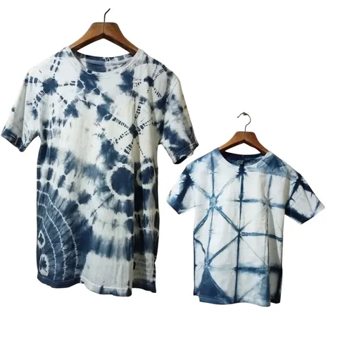 Dua kaos shibori biru tua dan putih ukuran dewasa dan anak pada gantungan baju
