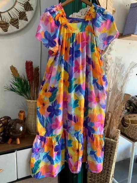Daster bermotif bunga besar warna-warni dengan rok bertingkat tergantung di hanger