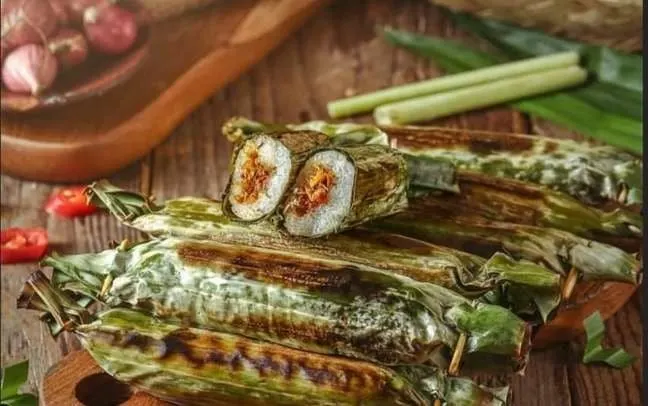 Lalampa, ketan gulung berbungkus daun pisang yang dibakar, satu terbuka menampilkan isian