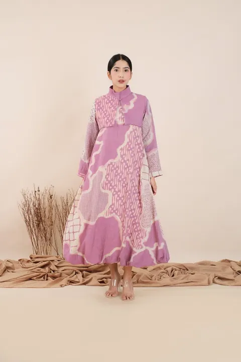 Model memakai dress panjang batik ungu muda dengan motif awan dan kotak di studio berlatar krem