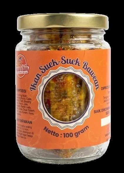 Toples kaca bertutup emas berlabel oranye Ikan Suek-Suek Bawean berisi suwiran ikan, netto 100 gram, berlatar hitam