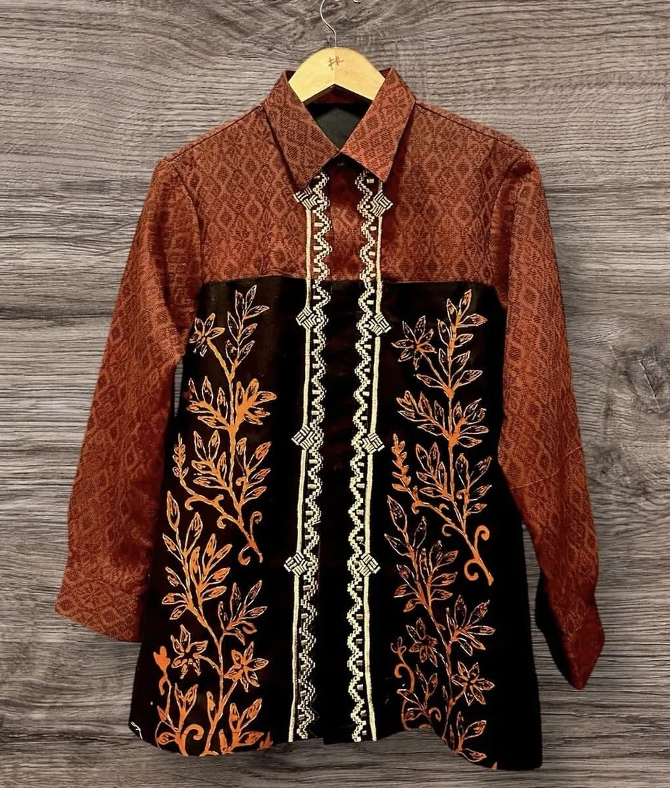 Kemeja lengan panjang motif merah bata dengan panel hitam berbordir daun oranye pada gantungan