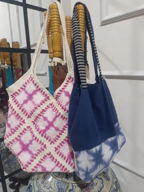 Tas bahu shibori merah muda berbingkai rajutan dan tas kain biru tua bermotif shibori biru putih tergantung