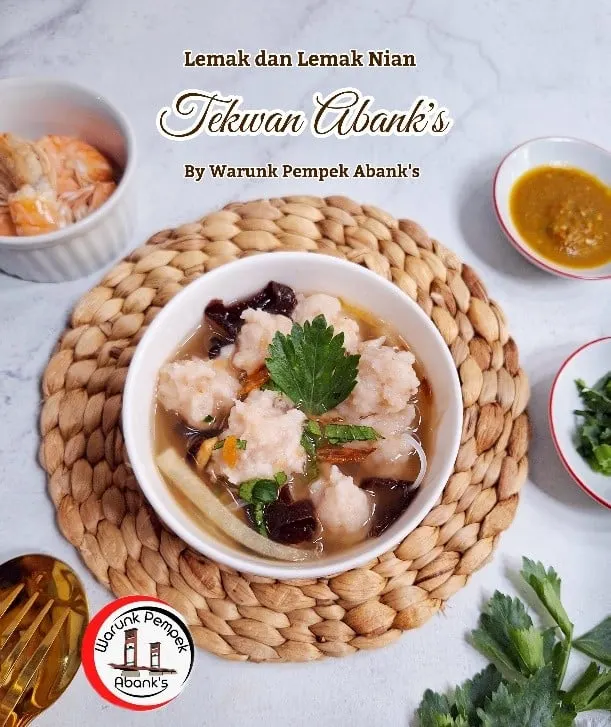 Semangkuk tekwan berkuah bening dengan jamur kuping dan daun seledri di atas tatakan anyaman