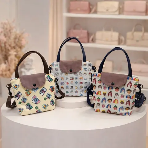 Tiga tas tangan kecil bermotif kamera dan wajah kartun dengan tutup cokelat di atas meja bundar putih