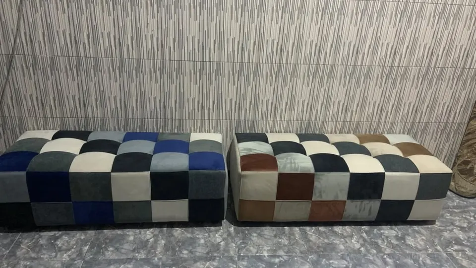 Dua puf panjang berlapis kain motif kotak-kotak biru, cokelat, abu-abu dan krem di depan dinding