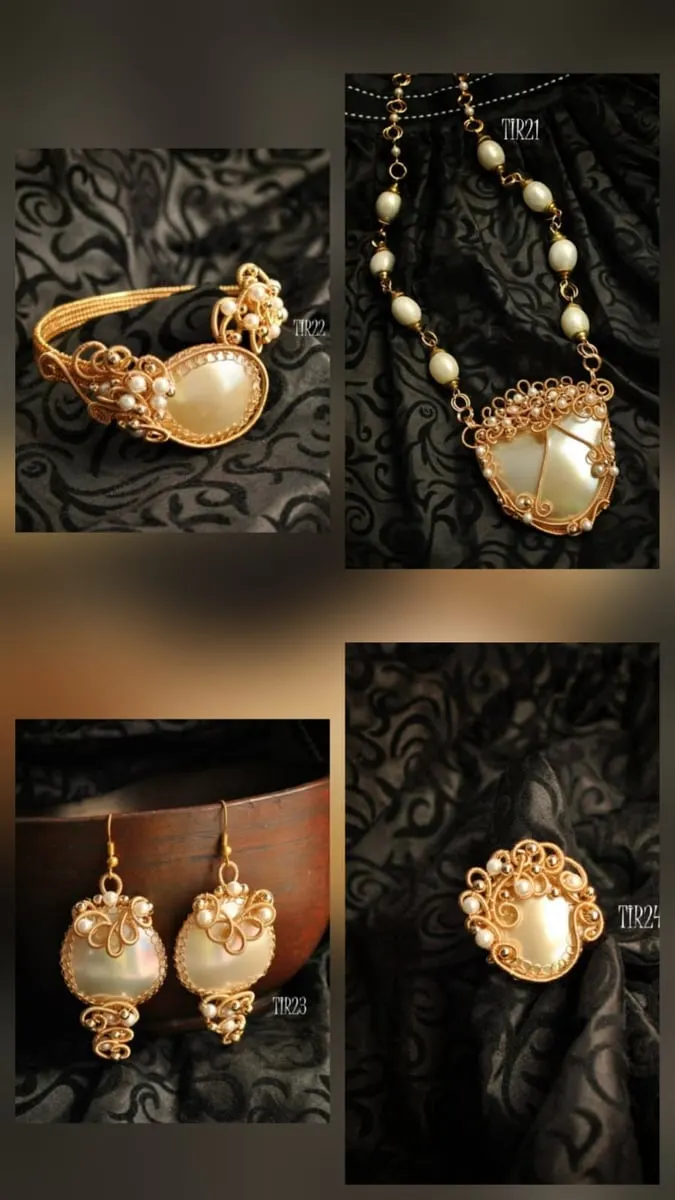 Gelang, kalung, anting dan cincin kawat keemasan dengan mutiara putih besar di atas kain hitam bermotif